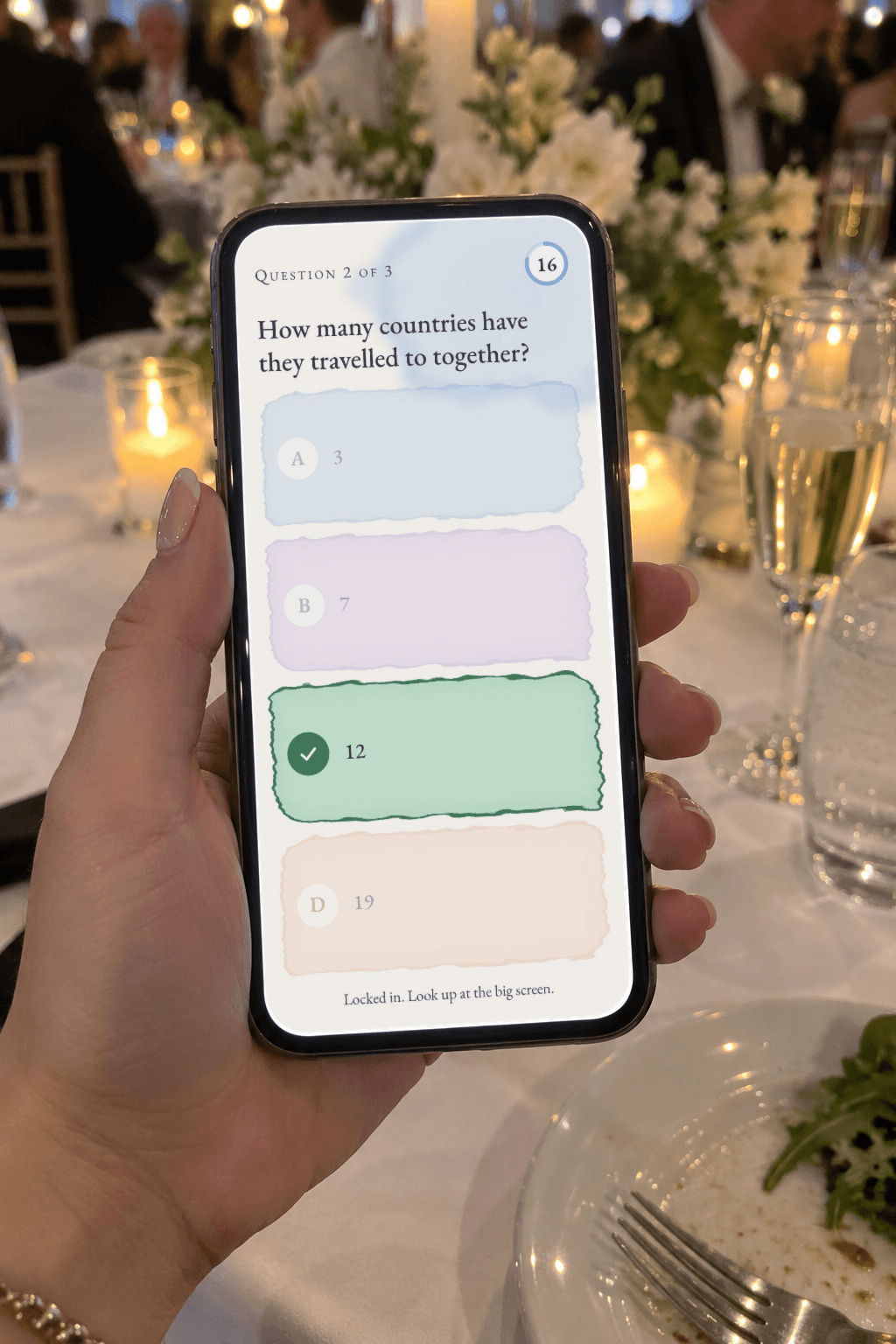 A guest's hand holding a phone with a Say Kampai answer screen